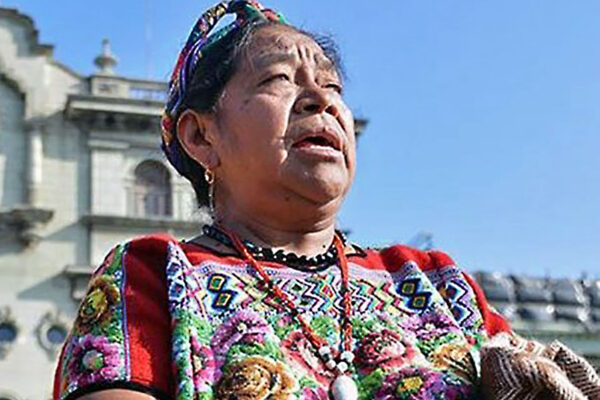 An older Cakchiquel Mayan woman in traditional dress examines the