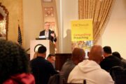 Richard Flory stands at podium in front of audience with Compelling Preaching banner behind him