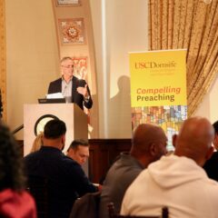 Richard Flory stands at podium in front of audience with Compelling Preaching banner behind him