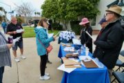 People gather around a table on sidewalk
