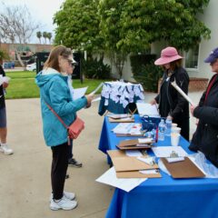 People gather around a table on sidewalk