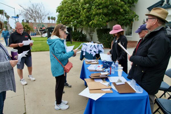 People gather around a table on sidewalk
