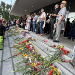 Flowers set on steps with religious clergy standing behind them