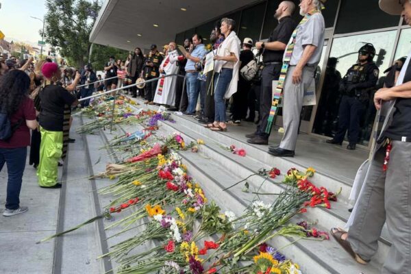 Flowers set on steps with religious clergy standing behind them