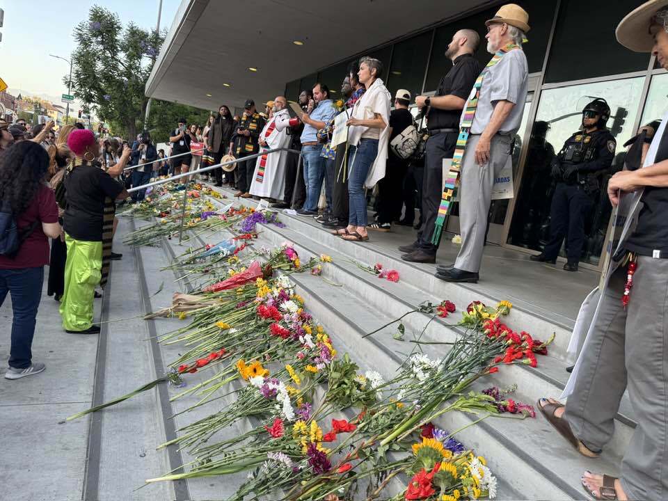 Flowers set on steps with religious clergy standing behind them